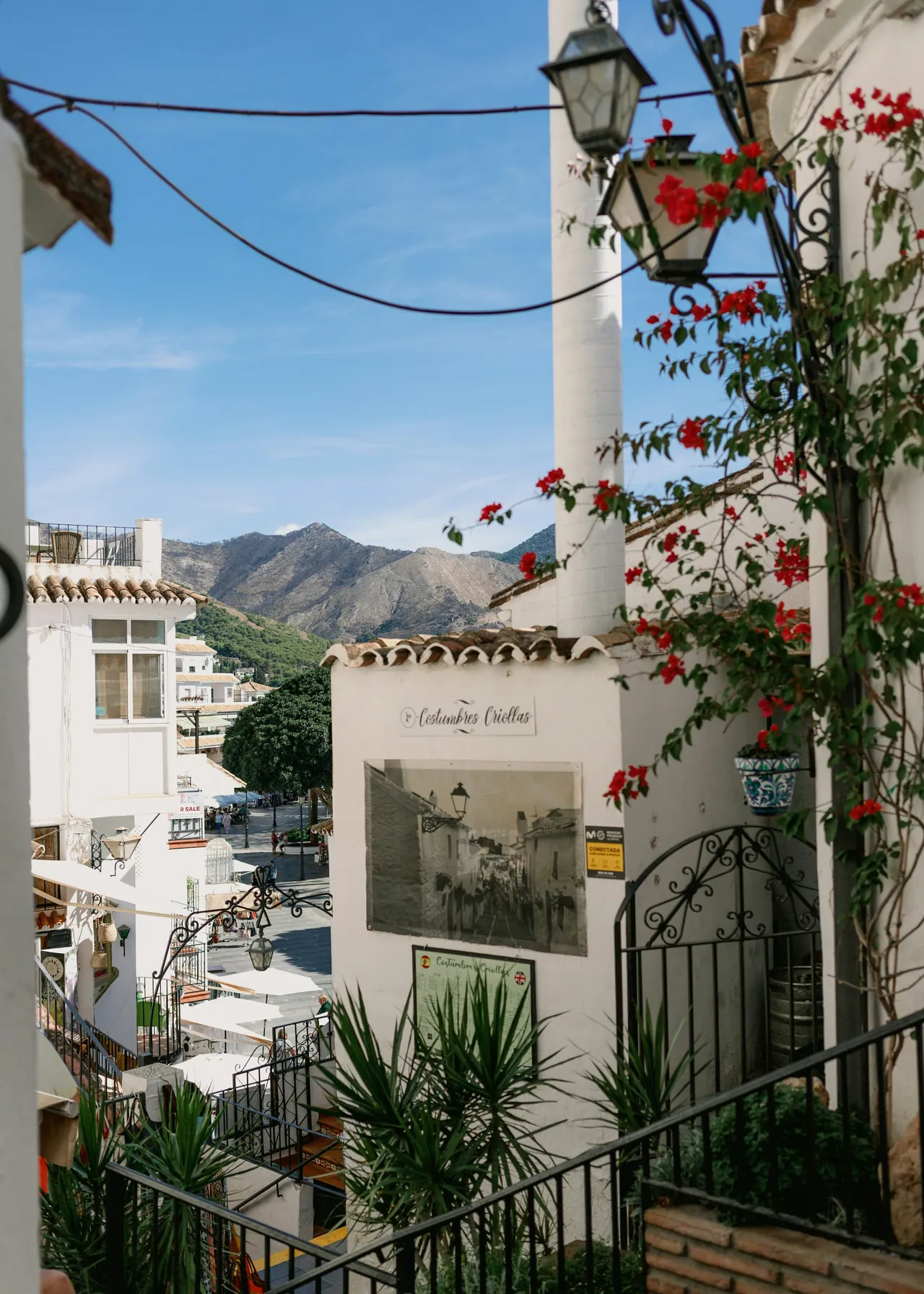 A whitewashed street corner with a clock and climbing flowers in Mijas Pueblo