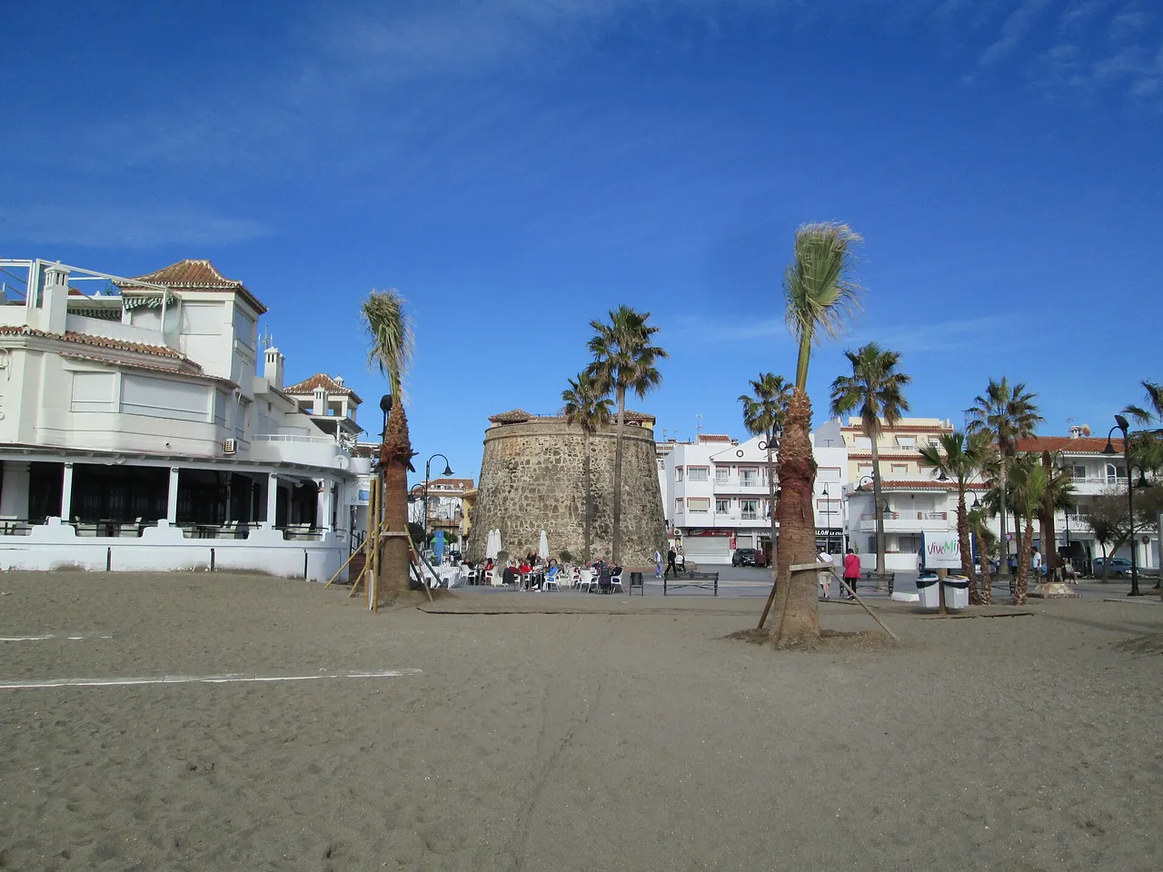 The beach of La Cala de Mijas with the old watchtower and palms