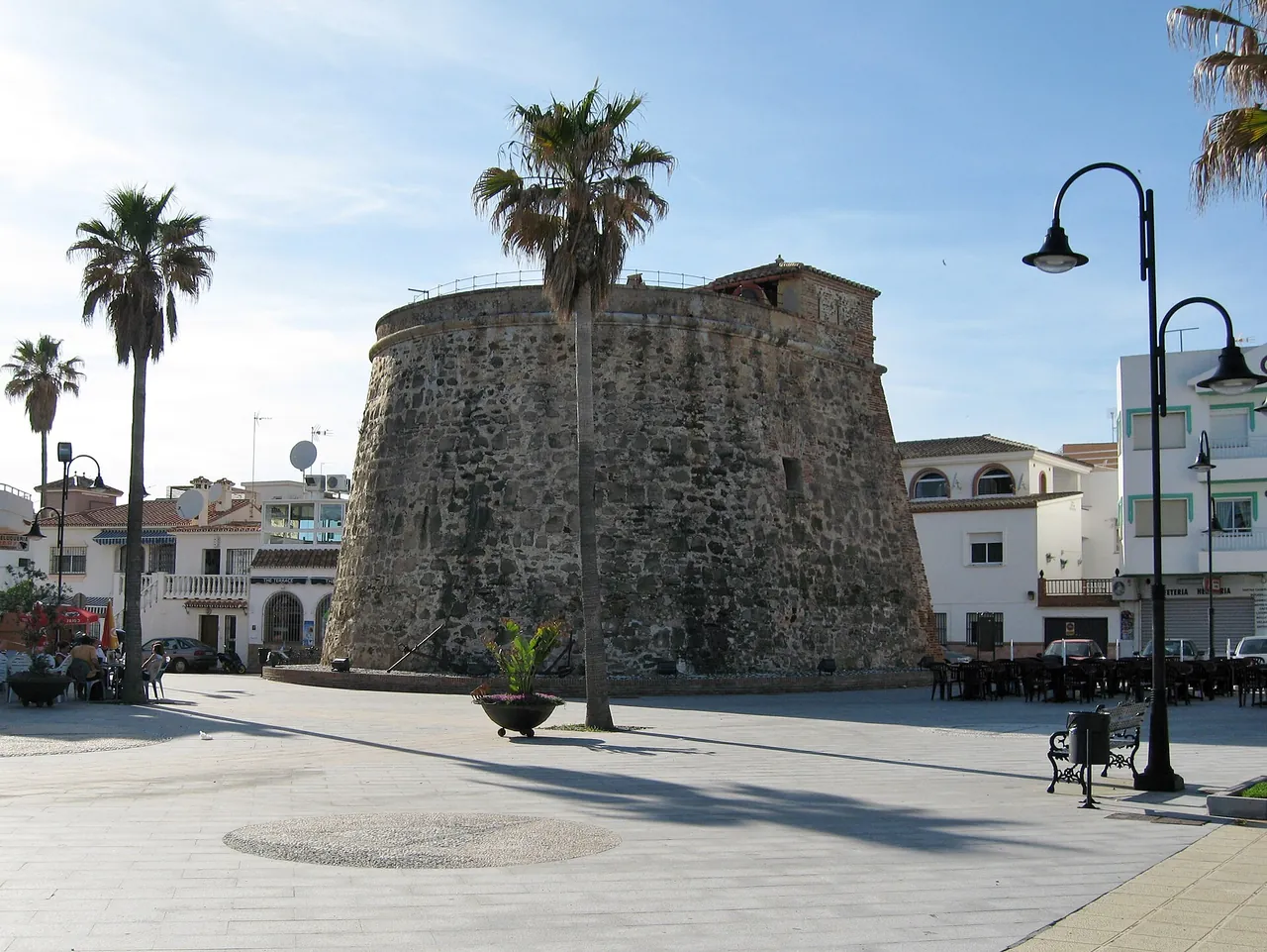 The old watchtower on the square beside the beach of La Cala de Mijas, with palms