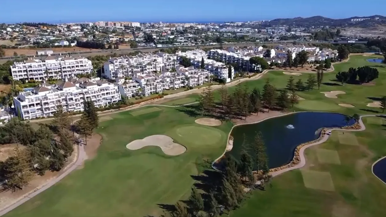 Mijas Golf from the air: fairways, a lake and apartments beside the course
