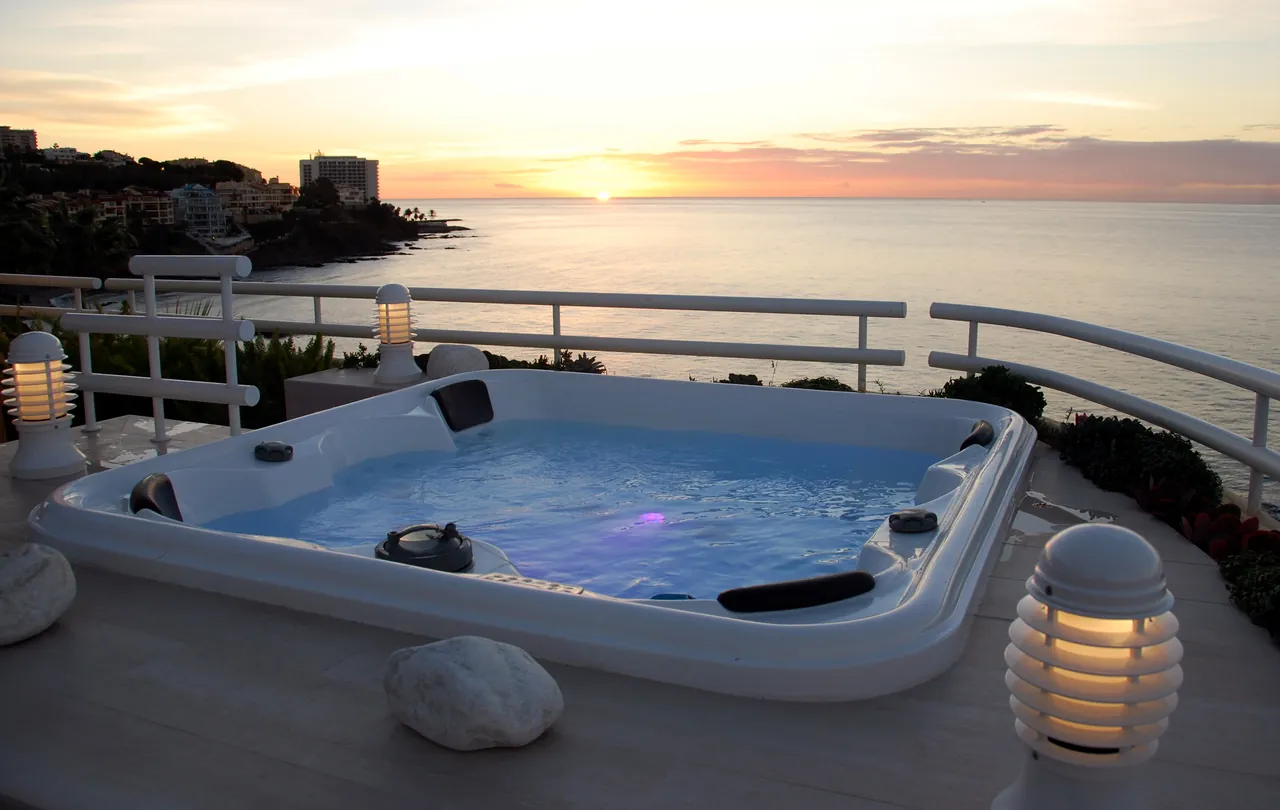 A penthouse terrace with a hot tub, looking over the sea at sunset