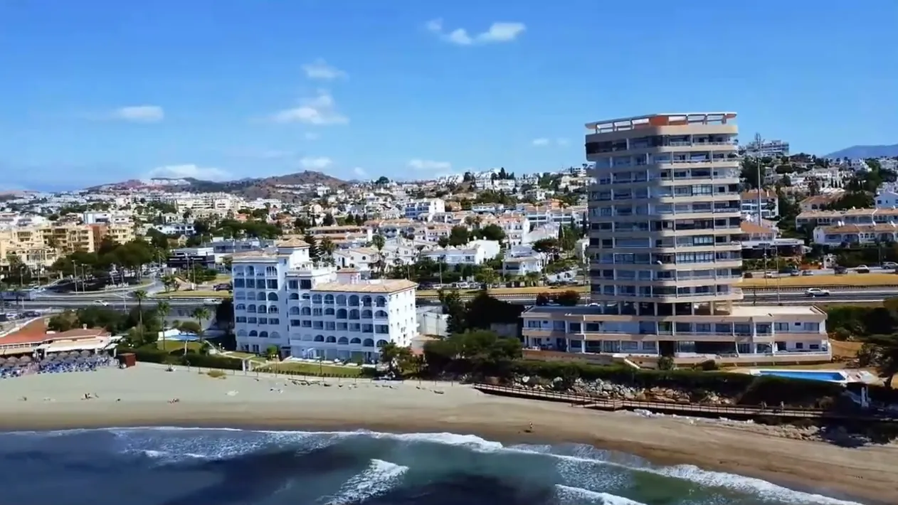 The beach at Riviera del Sol and its tall building by the sea, from the air
